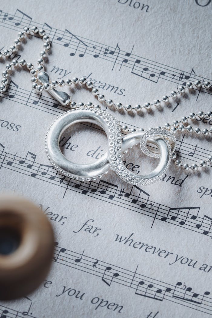 Silver infinity necklace elegantly placed on a music sheet symbolizing unity and harmony.